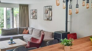 A living room with a sofa, chairs, a coffee table, a dining table, and a wall-mounted heater. - Gorgeous home in Sint-Oedenrode (Sint-Oedenrode)