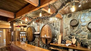 Eine rustikale Bar mit Holzhockern, Steinwänden und alten Leuchten.