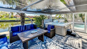Une terrasse extérieure avec un jacuzzi, des sièges rembourrés bleus et une table en bois.