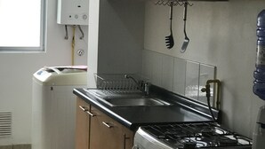 A kitchen with a gas stove, oven, sink, and a refrigerator. - Amplio y Cómodo Departamento Full Amoblado a Pasos de Chinchorro , Mall (Arica)