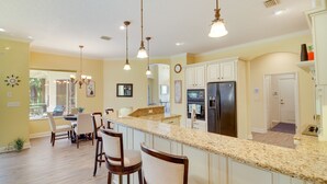 Una cocina amplia con encimera de granito, armarios blancos y un refrigerador negro.