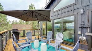 A deck with outdoor seating, a grill, and a large window overlooking a mountainous landscape. - Steps to Beach: Family Home w/ Views in Tahoe City (Tahoe City)