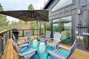 A deck with outdoor seating, a grill, and a large window overlooking a mountainous landscape. - Steps to Beach: Family Home w/ Views in Tahoe City (Tahoe City)