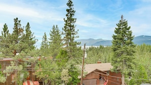 A cabin with a garage, surrounded by tall pine trees, with a mountain range in the background. - Steps to Beach: Family Home w/ Views in Tahoe City (Tahoe City)
