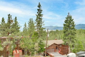 A cabin with a garage, surrounded by tall pine trees, with a mountain range in the background. - Steps to Beach: Family Home w/ Views in Tahoe City (Tahoe City)