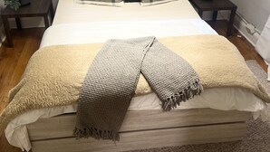 A neatly made bed with a beige blanket and a brown throw, flanked by two nightstands with lamps and a small plant. - Chic Madison Parkview
 (Albany)