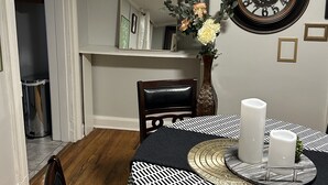 A dining area with a round table covered in a black and white checkered tablecloth, a vase with flowers, and a wall clock. - Chic Madison Parkview
 (Albany)