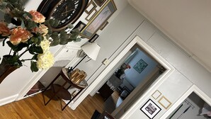 A room with a wooden floor, a clock, a vase with flowers, and framed pictures on the wall. - Chic Madison Parkview
 (Albany)