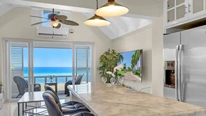 A modern kitchen with a large island, bar stools, a ceiling fan, and a view of the ocean. - Modern Apartment Montego Bay in Jamaica (Montego Bay)