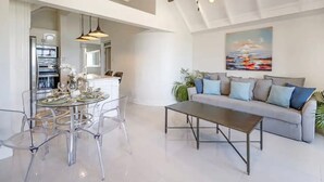 A spacious living area with a high ceiling, a dining table with chairs, a sofa, and a ceiling fan. - Modern Apartment Montego Bay in Jamaica (Montego Bay)