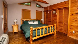 Une chambre à coucher avec un lit en bois, deux tables de chevet, un ventilateur de plafond et une grande fenêtre.
