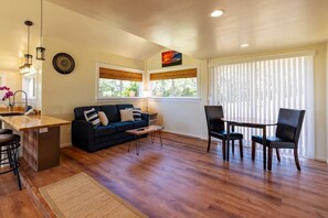 Open living room with queen couch bed, table, 65” TV, Bose sound system