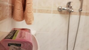 A bathroom with a shower, a towel rack, and a box of Palmolive soap.