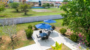 A patio area with a table and chairs, two blue umbrellas, and a potted plant. - Entire Accommodation Suites - Republic Terrace Accommodations (Republic Park, East Bank)