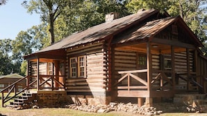 A rustic log cabin with a porch, stone foundation, and wooden railings. - Rustic Southern Cabin Near Stone Mountain Park • Cozy & Peaceful (Stone Mountain)