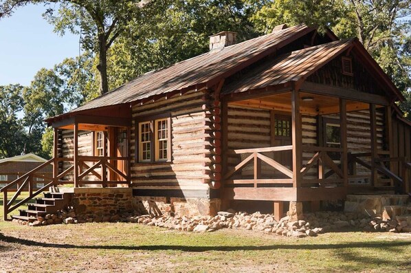 A rustic log cabin with a porch, stone foundation, and wooden railings. - Rustic Southern Cabin Near Stone Mountain Park • Cozy & Peaceful (Stone Mountain)