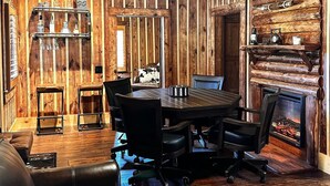 A rustic interior with a wooden ceiling, a fireplace, a dining area with a table and chairs, and a leather sofa. - Rustic Southern Cabin Near Stone Mountain Park • Cozy & Peaceful (Stone Mountain)
