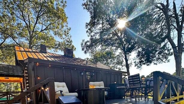 A wooden deck with outdoor seating, a fire pit, and a building with a sloped roof. - Rustic Southern Cabin Near Stone Mountain Park • Cozy & Peaceful (Stone Mountain)