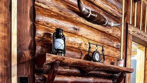 A log fireplace with a clock and lantern on a shelf above it. - Rustic Southern Cabin Near Stone Mountain Park • Cozy & Peaceful (Stone Mountain)