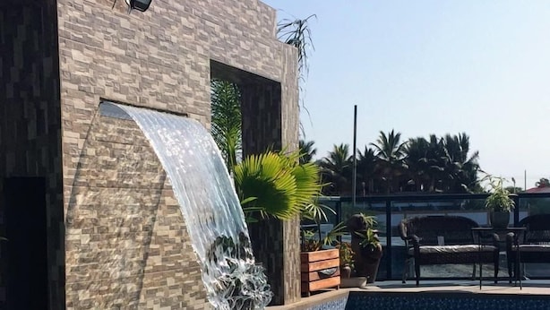 Une piscine agrémentée d’une cascade, un mur en pierre et du mobilier d’extérieur.