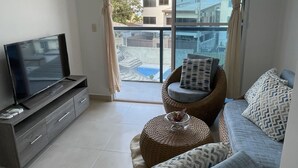 Un salon moderne avec un téléviseur à écran plat, un canapé et un fauteuil en osier.