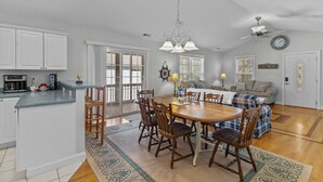 A spacious kitchen with white cabinets, a dining area with a wooden table and chairs, and a living room with a sofa and a coffee table. - 5min to Attractions, Shops & Beach and Yard Games (Oak Island)