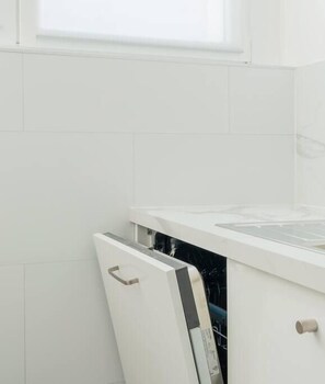 Une cuisine avec des meubles blancs et un lave-vaisselle.