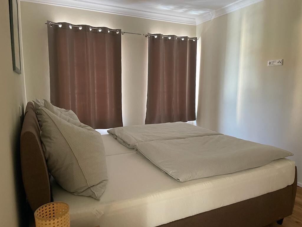 A single bed with a headboard, two pillows, and a wooden floor.