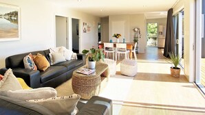 Un salon spacieux avec un canapé noir, une table basse et un coin repas comprenant une table et des chaises.