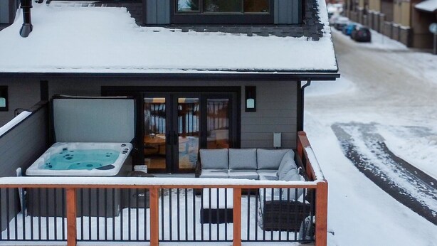 Un chalet à deux étages doté d’un balcon et d’un jacuzzi.