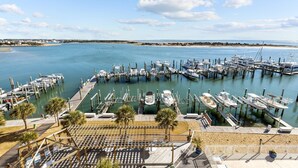 Una marina con barcos amarrados en muelles de madera, una playa arenosa al fondo y un cielo despejado.