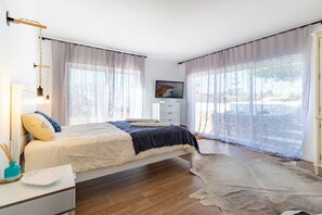 A bedroom with a bed, a TV, a desk, and a large window. - Casa Boa Vida (Carvoeiro)
