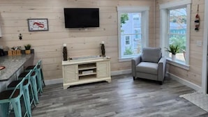 Una cucina moderna con TV integrata, sgabelli da bar e una finestra vista edifici.