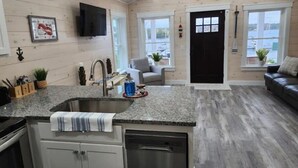Una cucina con piani in granito, lavastoviglie in acciaio inossidabile e una porta nera.