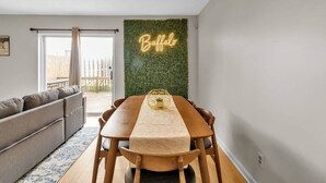 Ein Essbereich mit Holztisch, Stühlen und einem Neonlichtschild an der Wand.