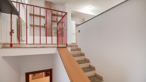 Un escalier avec une rampe en bois et des balustres en métal rouge.