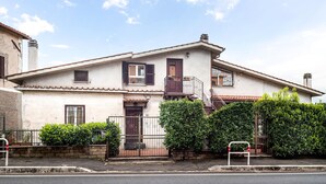 Une maison à deux étages avec un balcon, une entrée sécurisée par un portail et un petit jardin.