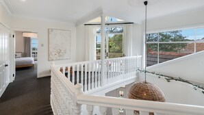 Et værelse med en seng, et stort vindue og en balkon med gelænder.
