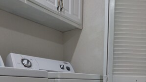 A laundry area with two white washing machines and a white cabinet above them. - Idyllic serene secure condo minutes from beach & amenities.  (Bridgetown)