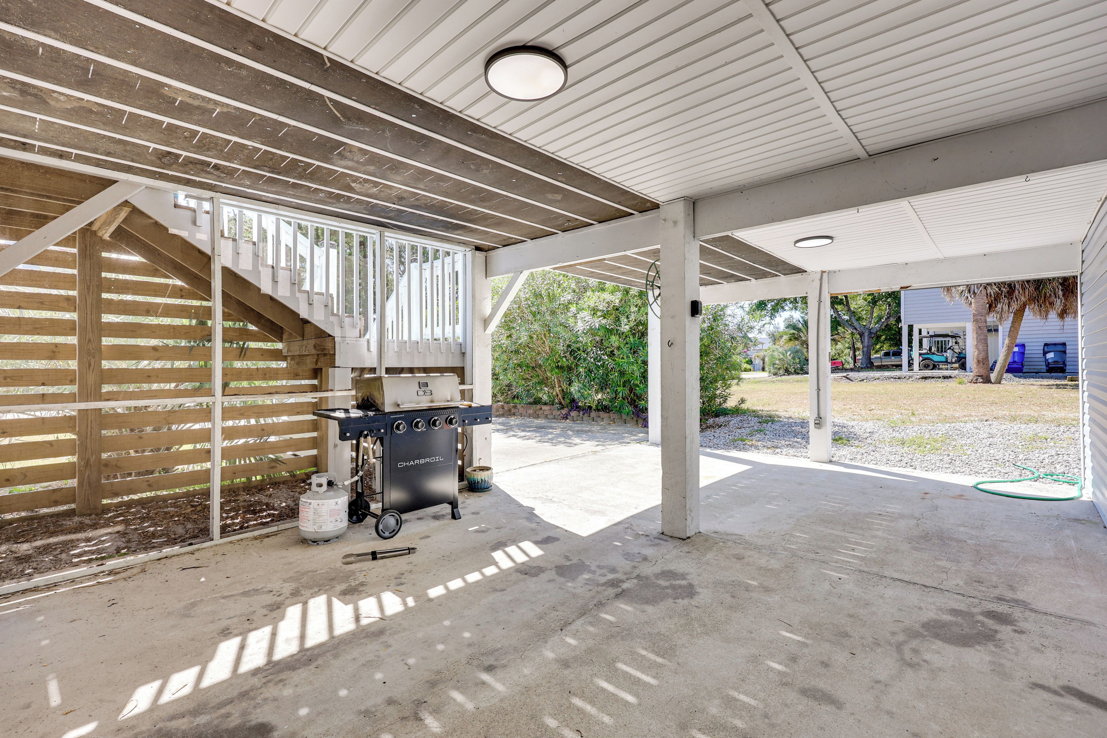 A covered outdoor area with a barbecue grill, concrete floor, and wooden beams.