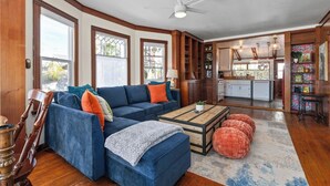 Una sala de estar con un sofá modular, otomanas, una mesa de centro y una cocina al fondo.