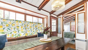 Una habitación con un banco de madera, una mesa con una planta, una cortina estampada y una araña.