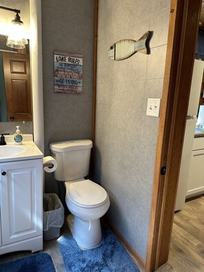 Ein Badezimmer mit Toilette, Waschbecken und einem Schild an der Wand.
