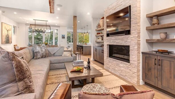 A modern living room with a stone fireplace, a sofa, and a dining area. - Abode at Sugar Magnolia, outdoor living, private hot tub, Jackson (Jackson)