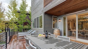 A wooden deck with a table and chairs, a wine bottle, and a barrel. - Abode at Sugar Magnolia, outdoor living, private hot tub, Jackson (Jackson)