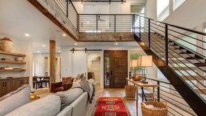 A spacious living area with a high ceiling, a staircase, and a cozy seating area. - Abode at Sugar Magnolia, outdoor living, private hot tub, Jackson (Jackson)