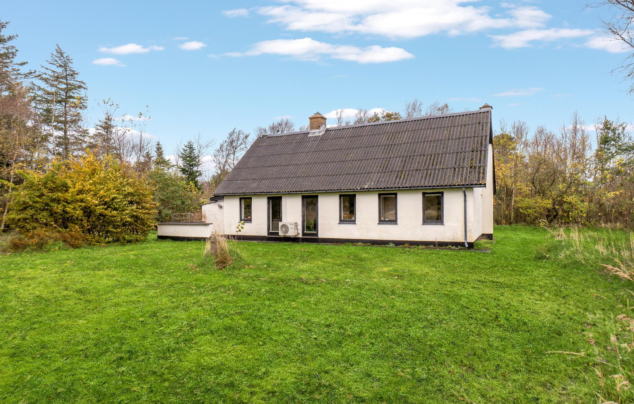 Une maison de plain-pied avec un toit en pente, une cheminée et un petit porche.