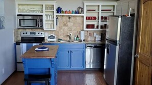 A compact kitchen with a blue island, stainless steel appliances, and white cabinetry. - Lakeview Hideaway - Amazing View of Lake of the Arbuckles (Sulphur)