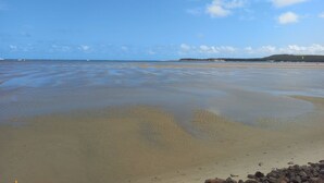 A beach with a wide expanse of sand and gentle waves. - Casa Paraíso das Conchas (Barra de São Miguel)