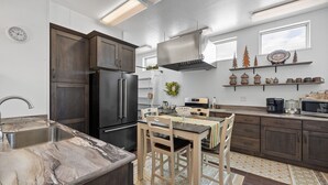 Een moderne keuken met donkerhouten kastjes, een roestvrijstalen koelkast en een marmeren aanrecht.